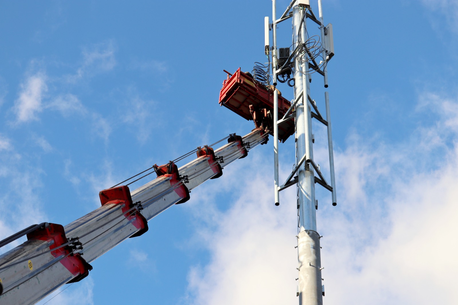 Crane lifting equipment during build-to-suit cell tower construction